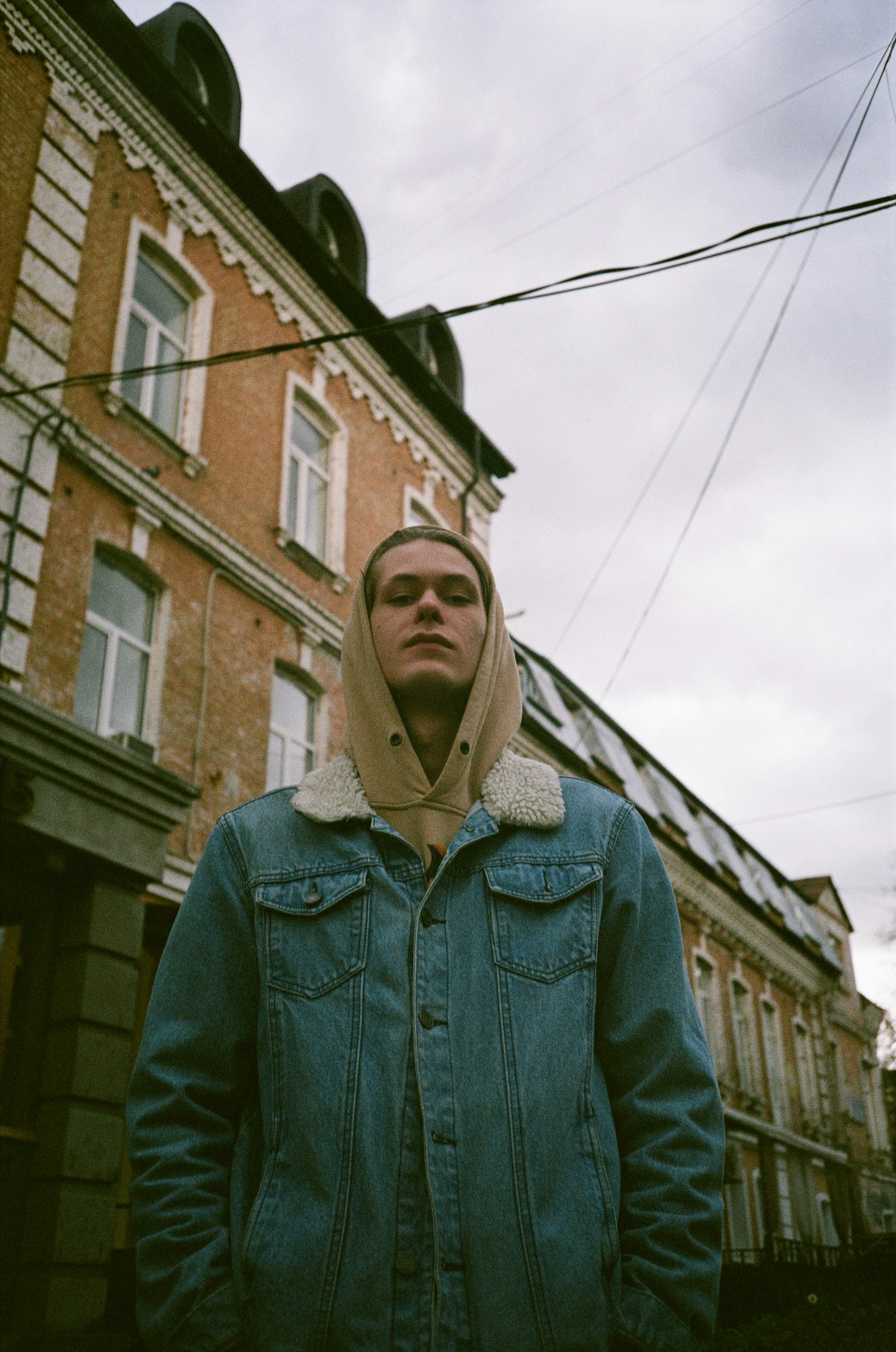 woman in blue denim jacket standing near brown concrete building during daytime